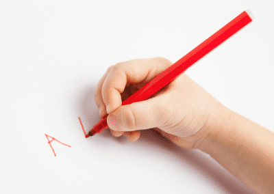 child writing with red pen Alphabets